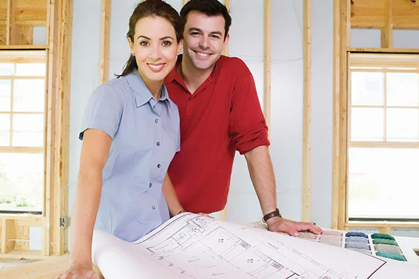 Young couple looking over construction blueprints with their home