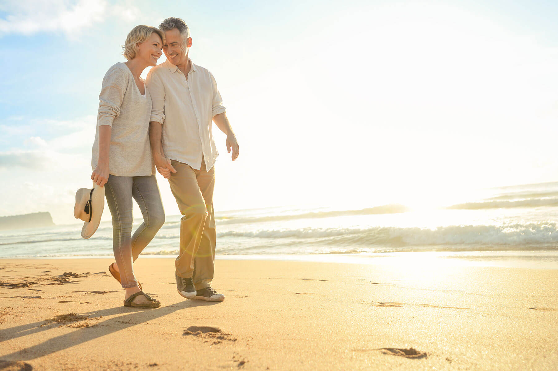 Senior couple smiling and walking on the beach