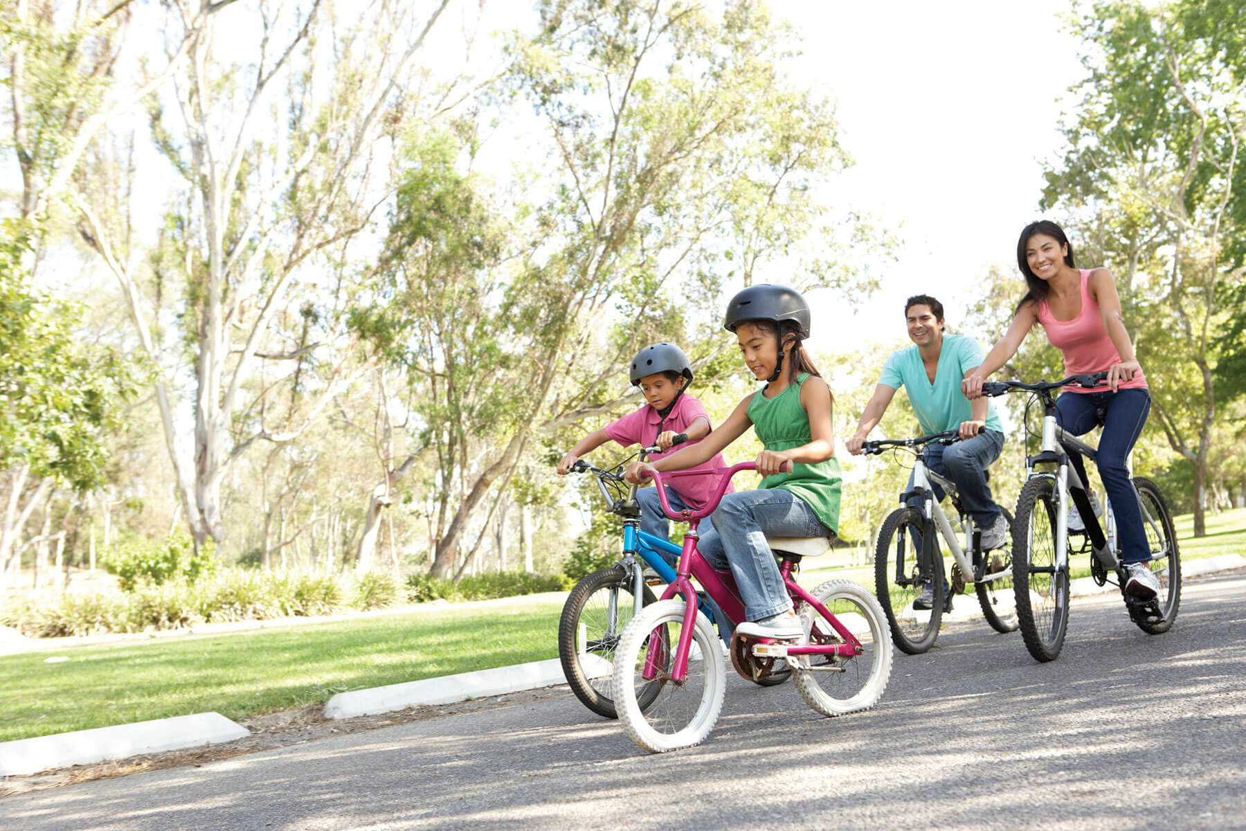 Family riding bikes on a road through a park
